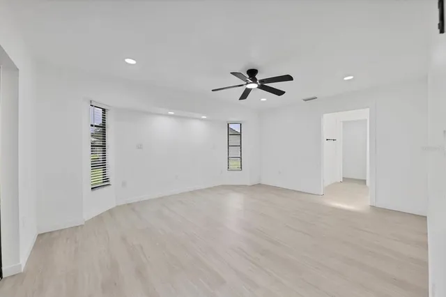 a view of empty room with wooden floor and ceiling fan