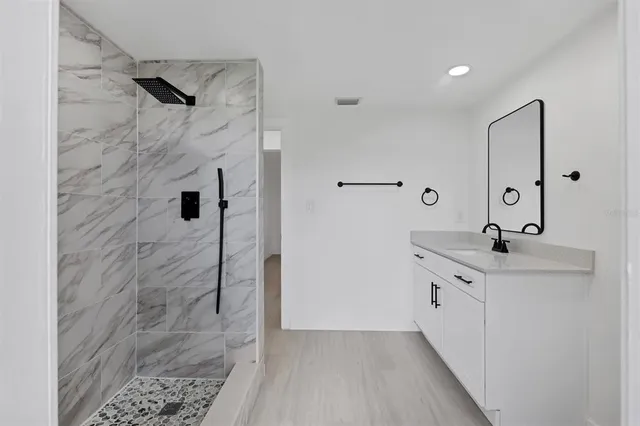 a bathroom with a granite countertop sink a mirror and shower