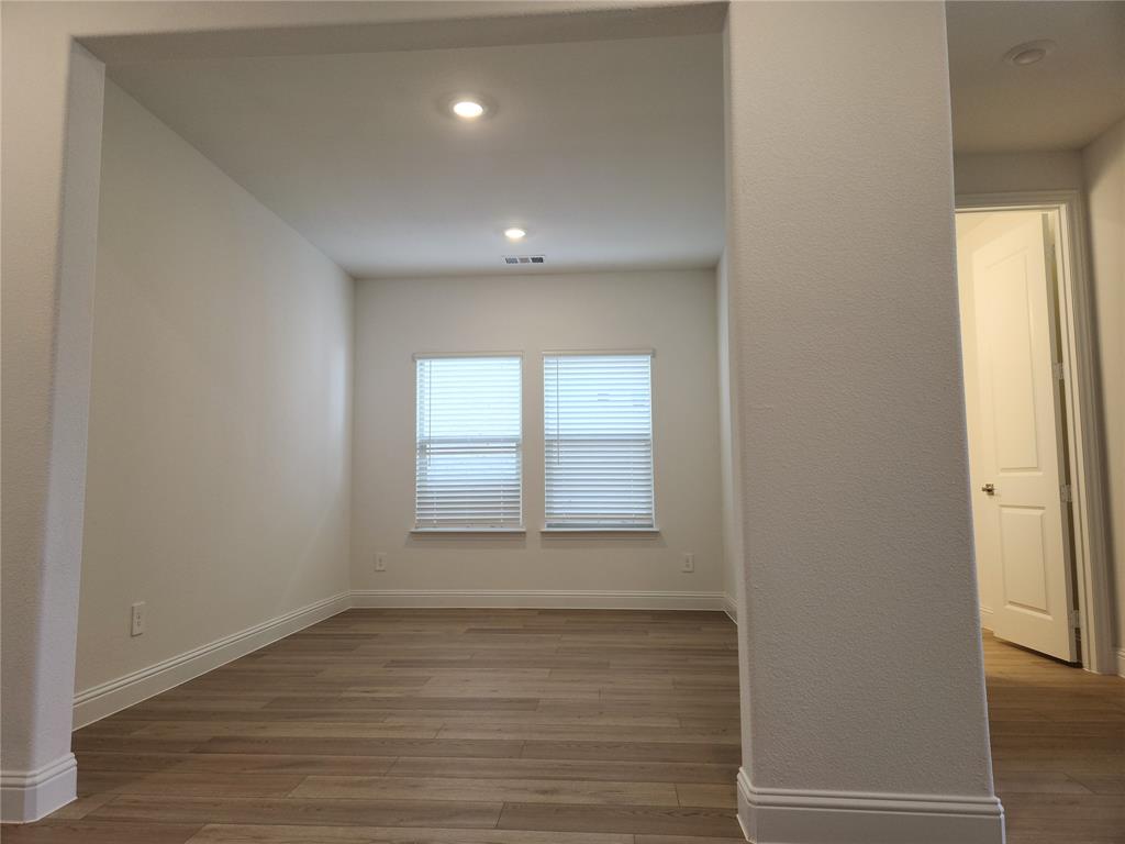 2433 Glacier Ridge Corinth, TX 76210 - Photo 8 of 40 a view of an empty room with wooden floor and a window