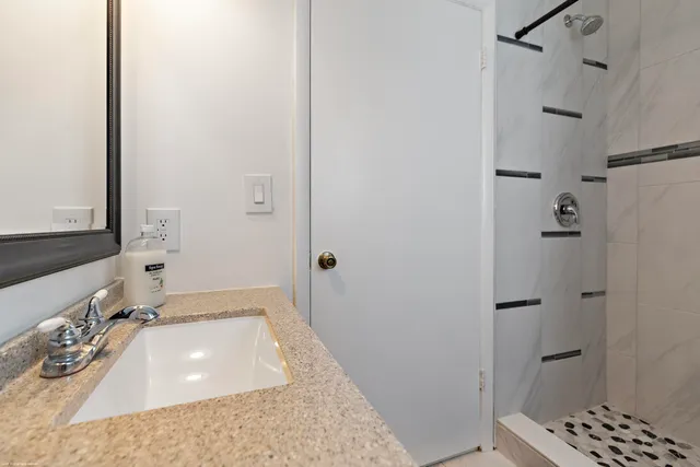 a bathroom with a granite countertop sink a shower and a mirror