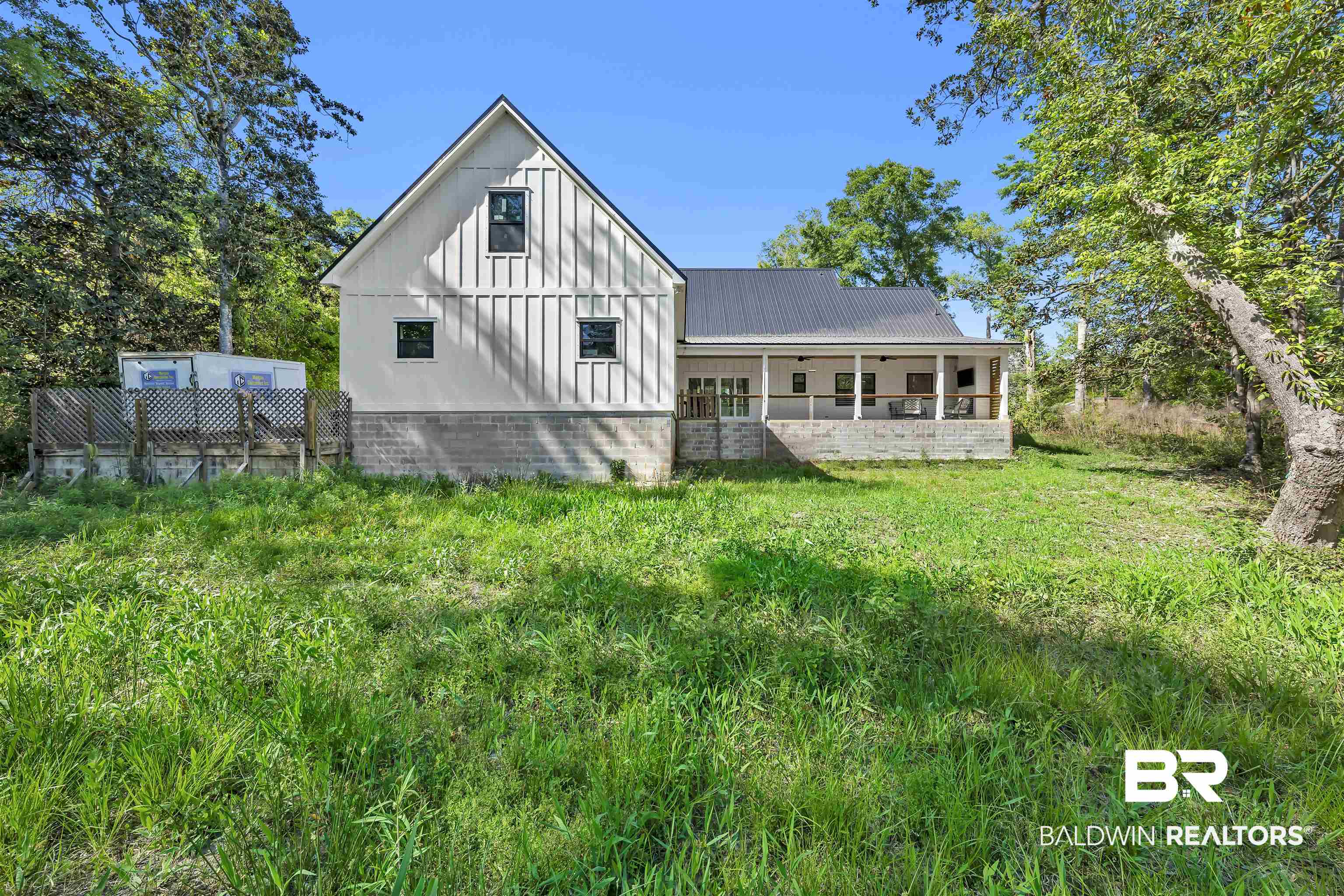 19058 James Road Gulf Shores, AL 36542 - Photo 42 of 49 Rear view of house with board and batten siding, a yard, and a porch