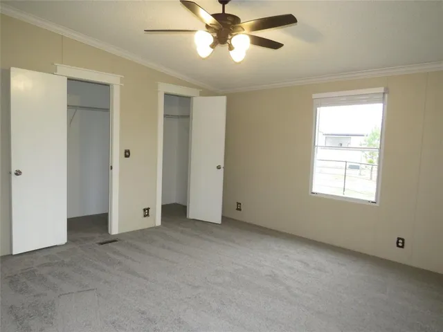 a view of an empty room and chandelier fan