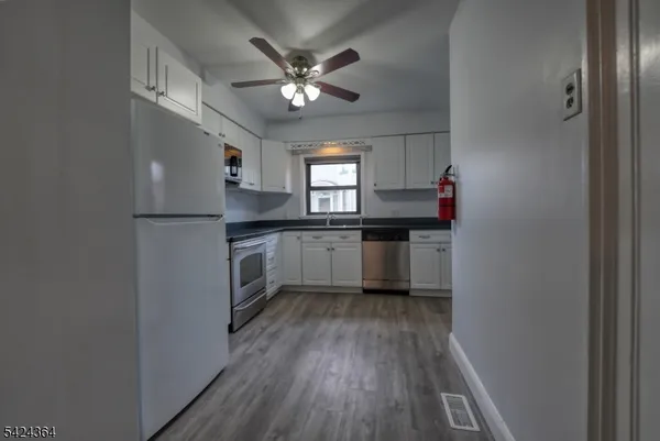 a kitchen with stainless steel appliances granite countertop a refrigerator a sink a stove and white cabinets