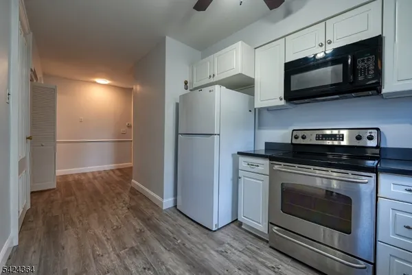 a kitchen with stainless steel appliances a stove a microwave and a hard wood floor
