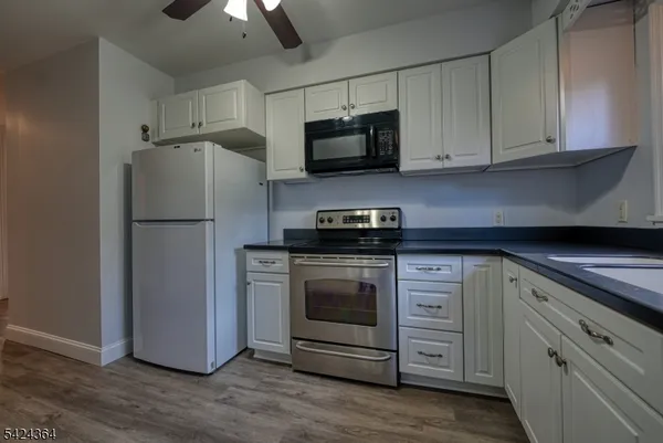 a kitchen with stainless steel appliances white cabinets white stove a microwave and a refrigerator