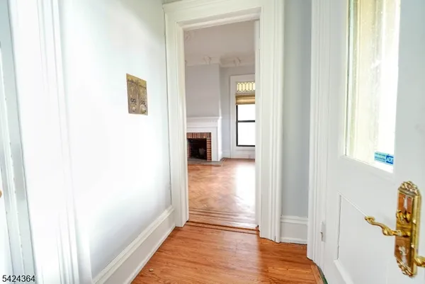 a view of a hallway with wooden floor and a bathroom