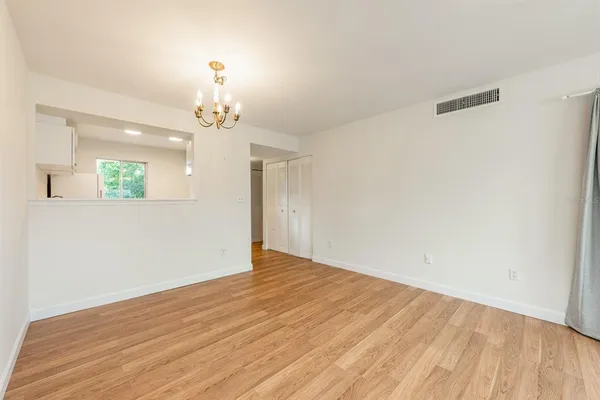 an empty room with wooden floor closet and windows