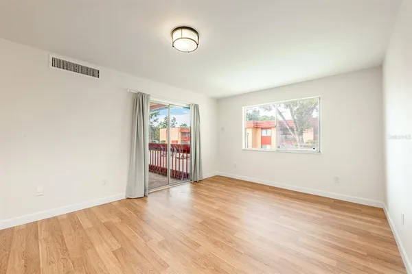 a view of empty room with wooden floor and fan
