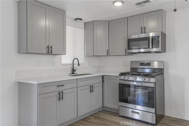a kitchen with stainless steel appliances granite countertop white cabinets a sink a stove and a microwave