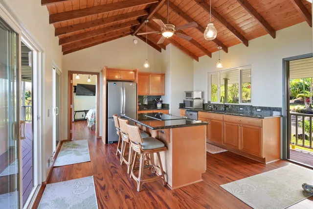 a kitchen with stainless steel appliances granite countertop a refrigerator a sink dishwasher a stove and white countertops with wooden floor