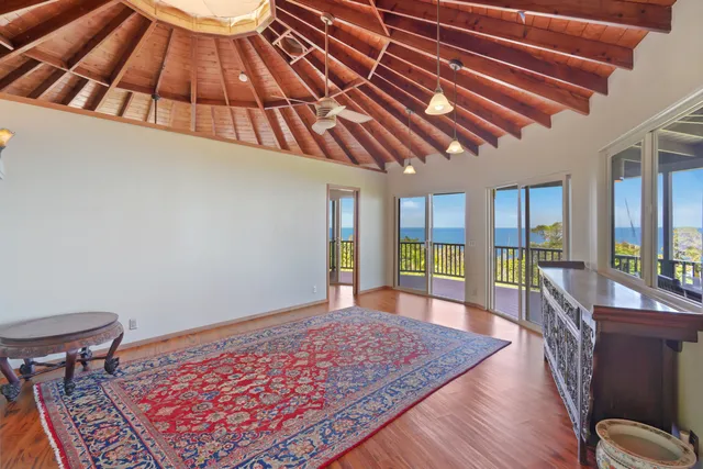 a view of an empty room with wooden floor and furniture