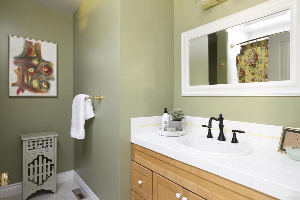 594 Rancho Santa Fe Road Encinitas, CA 92024 - Photo 27 of 47 a bathroom with a sink a mirror and painting on the wall