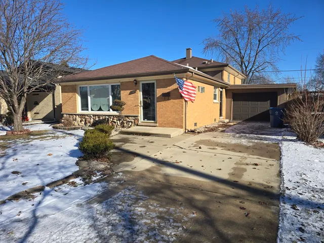 a front view of a house with a yard covered with snow and cars