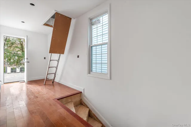 a view of an empty room with window and wooden floor