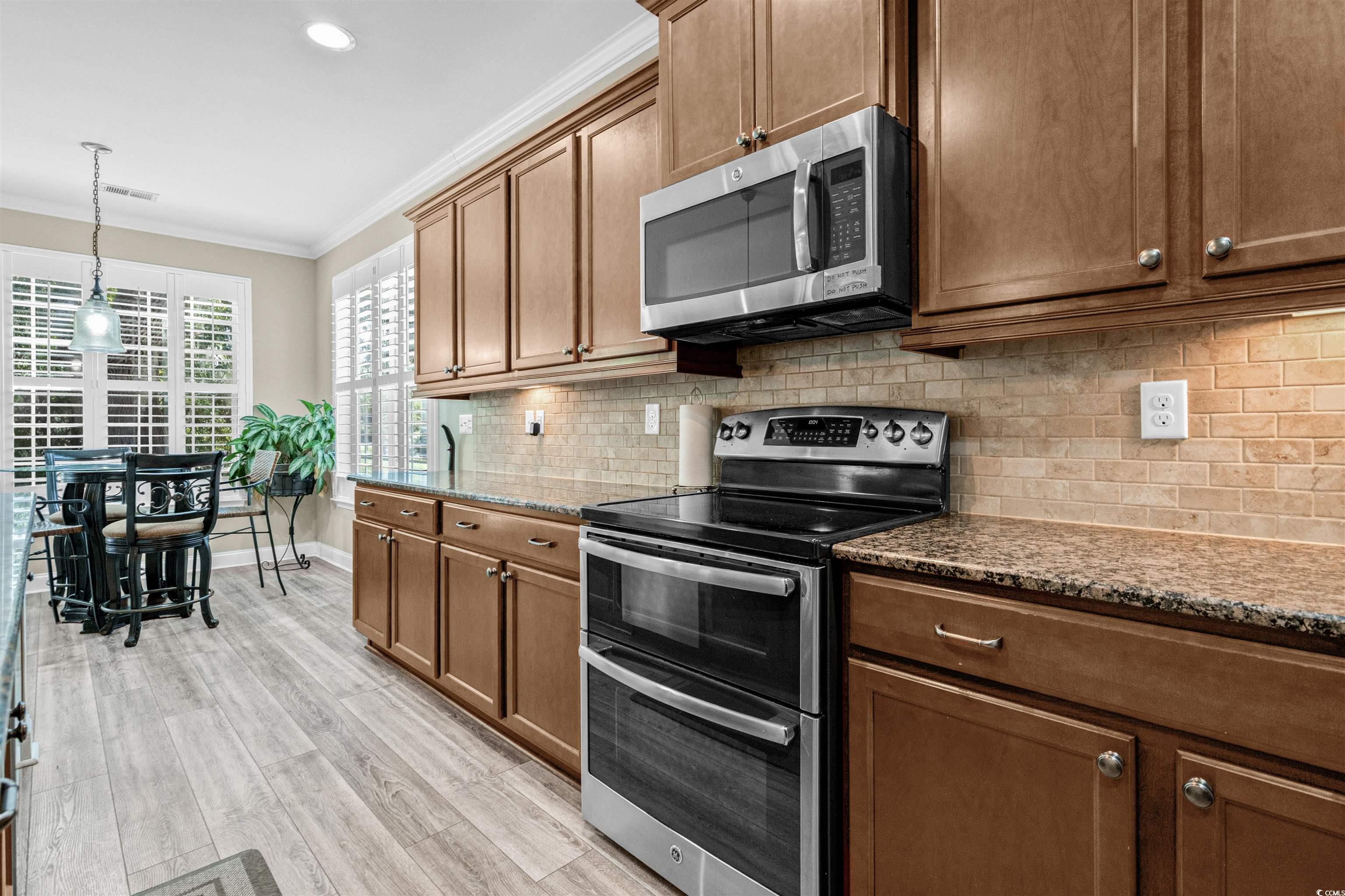 131 Gilman Road Pawleys Island, SC 29585 - Photo 15 of 40 Kitchen with stainless steel appliances, ornamental molding, dark stone countertops, backsplash, and pendant lighting