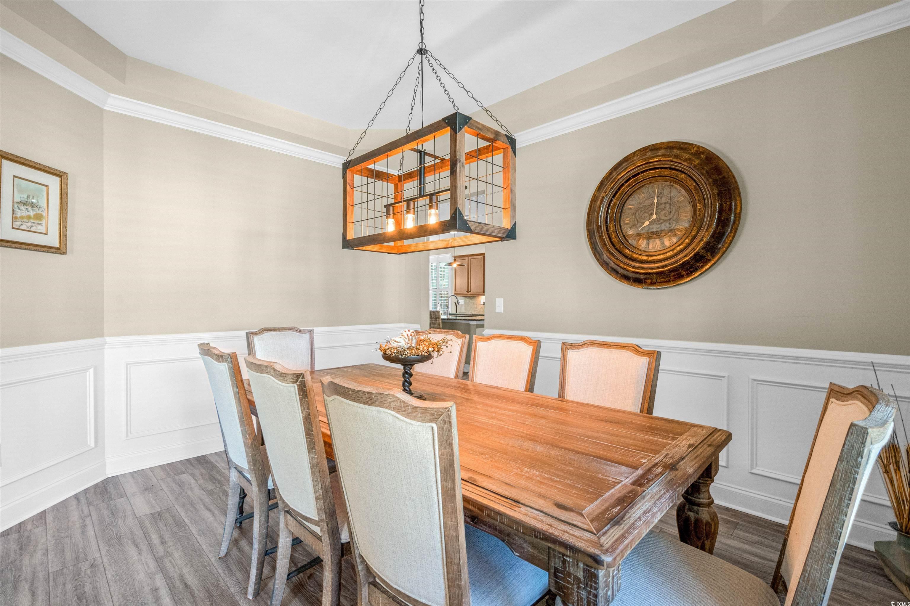 Dining room with a decorative wall, wainscoting, wood finished floors, and crown molding