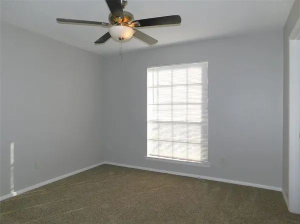 an empty room with a window and a fan