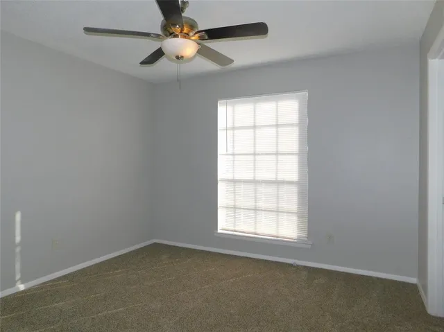 an empty room with a window and a fan