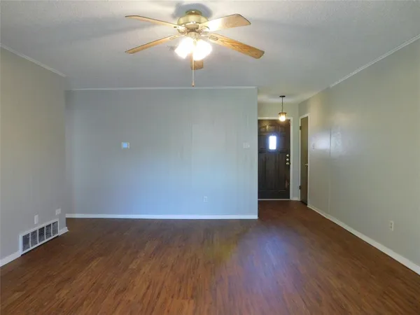 an empty room with wooden floor closet and fan