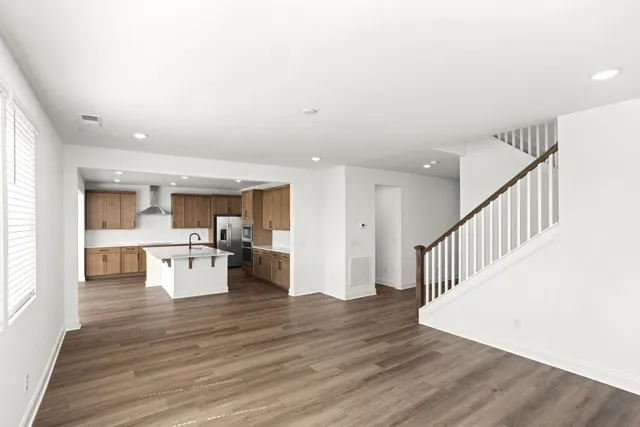a dining hall with wooden floor and a view of living room