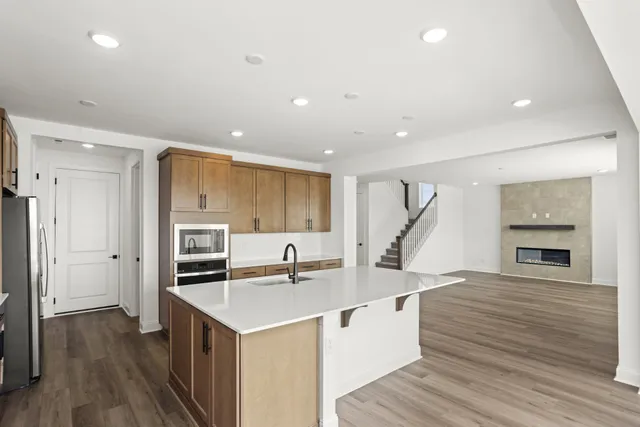 a kitchen with stainless steel appliances granite countertop a refrigerator a stove and a wooden floors