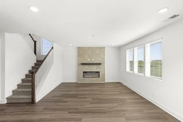 a view of an empty room with wooden floor fireplace and a window