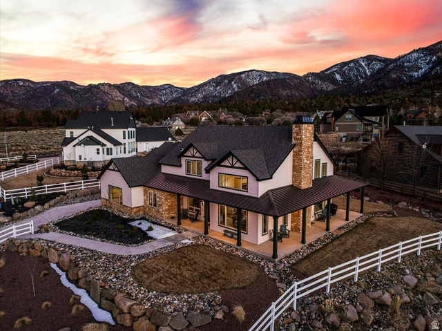 1210 East Bristle Cone Road Pine Valley, UT 84781 - Photo 3 of 54 Back of property at dusk featuring a fenced backyard, a porch, stone siding, a mountain view, and a chimney