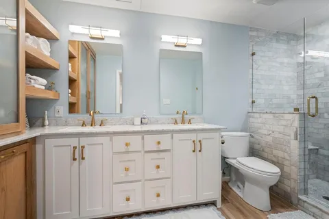 a spacious bathroom with a double vanity sink a toilet and a mirror