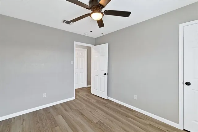 an empty room with ceiling fan and wooden floor