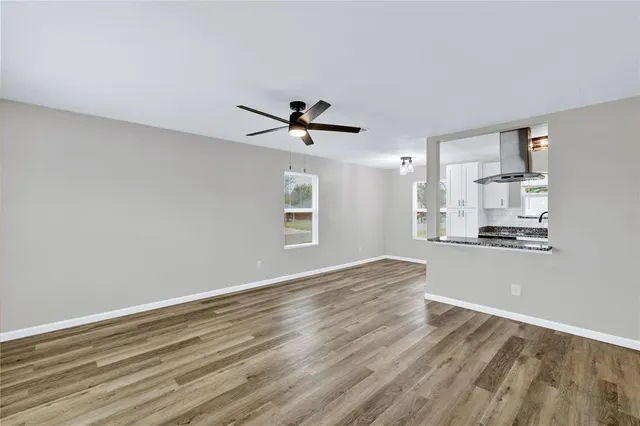 a view of empty room with wooden floor and ceiling fan