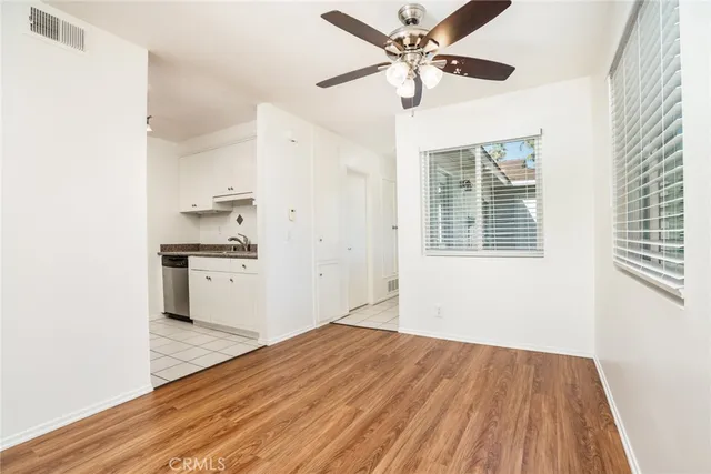 a view of kitchen and empty room with wooden floor