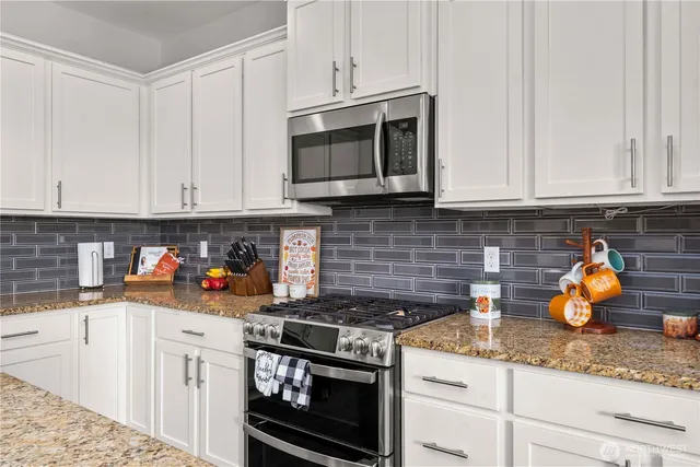a kitchen with stainless steel appliances granite countertop a stove a microwave and cabinets