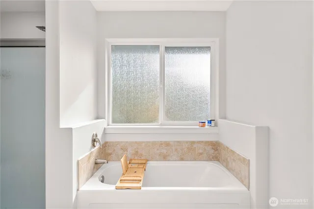 a white bath tub sitting in a bathroom next to a window