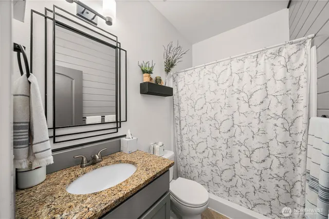 a bathroom with a granite countertop toilet sink and mirror