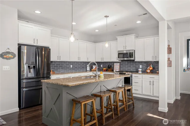 a kitchen with stainless steel appliances granite countertop a white cabinets and a refrigerator