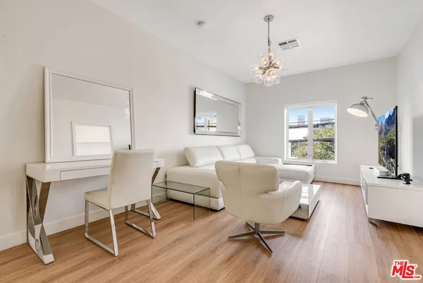 a living room with furniture two window and a flat screen tv