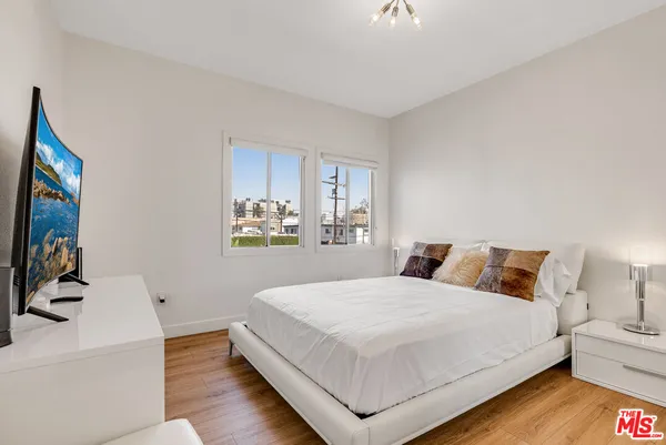 a bedroom with a bed and a flat tv screen on dresser