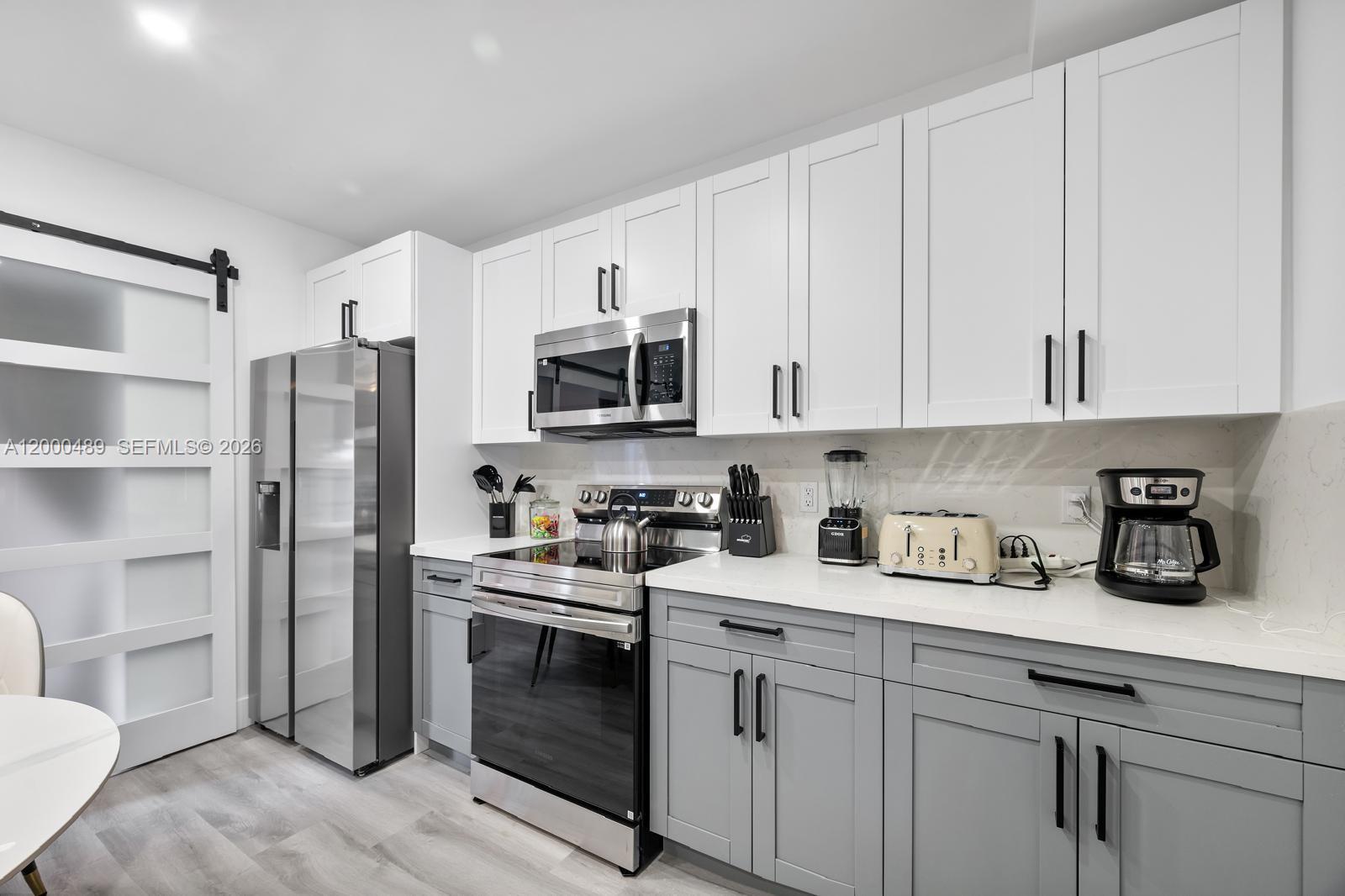 11730 Northwest 3rd Avenue Miami, FL 33168 - Photo 7 of 39 a kitchen with stainless steel appliances granite countertop white cabinets a refrigerator a sink a stove a microwave and wooden floors