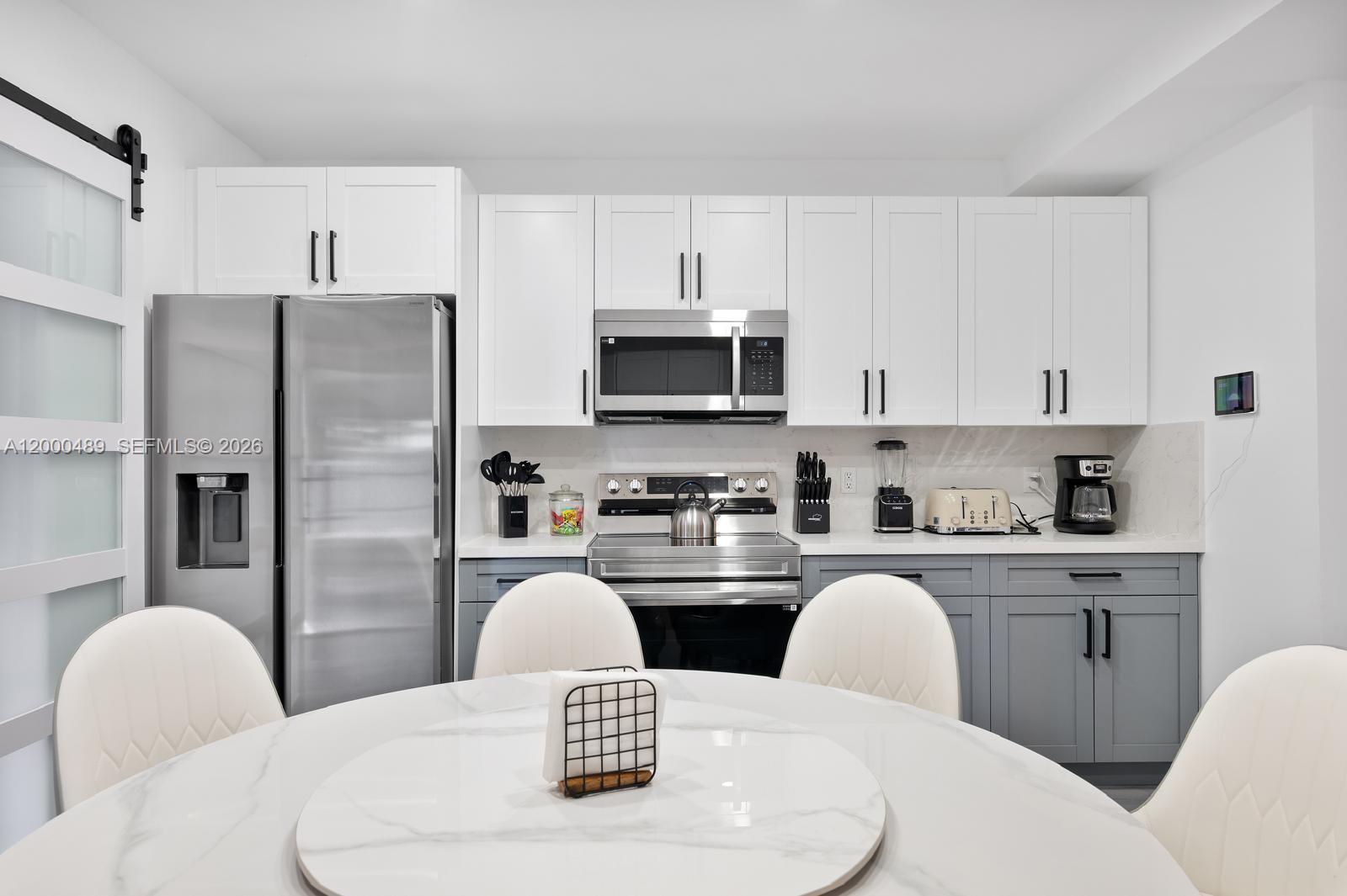11730 Northwest 3rd Avenue Miami, FL 33168 - Photo 8 of 39 a kitchen with stainless steel appliances granite countertop a white refrigerator a microwave a stove a dining table and chairs