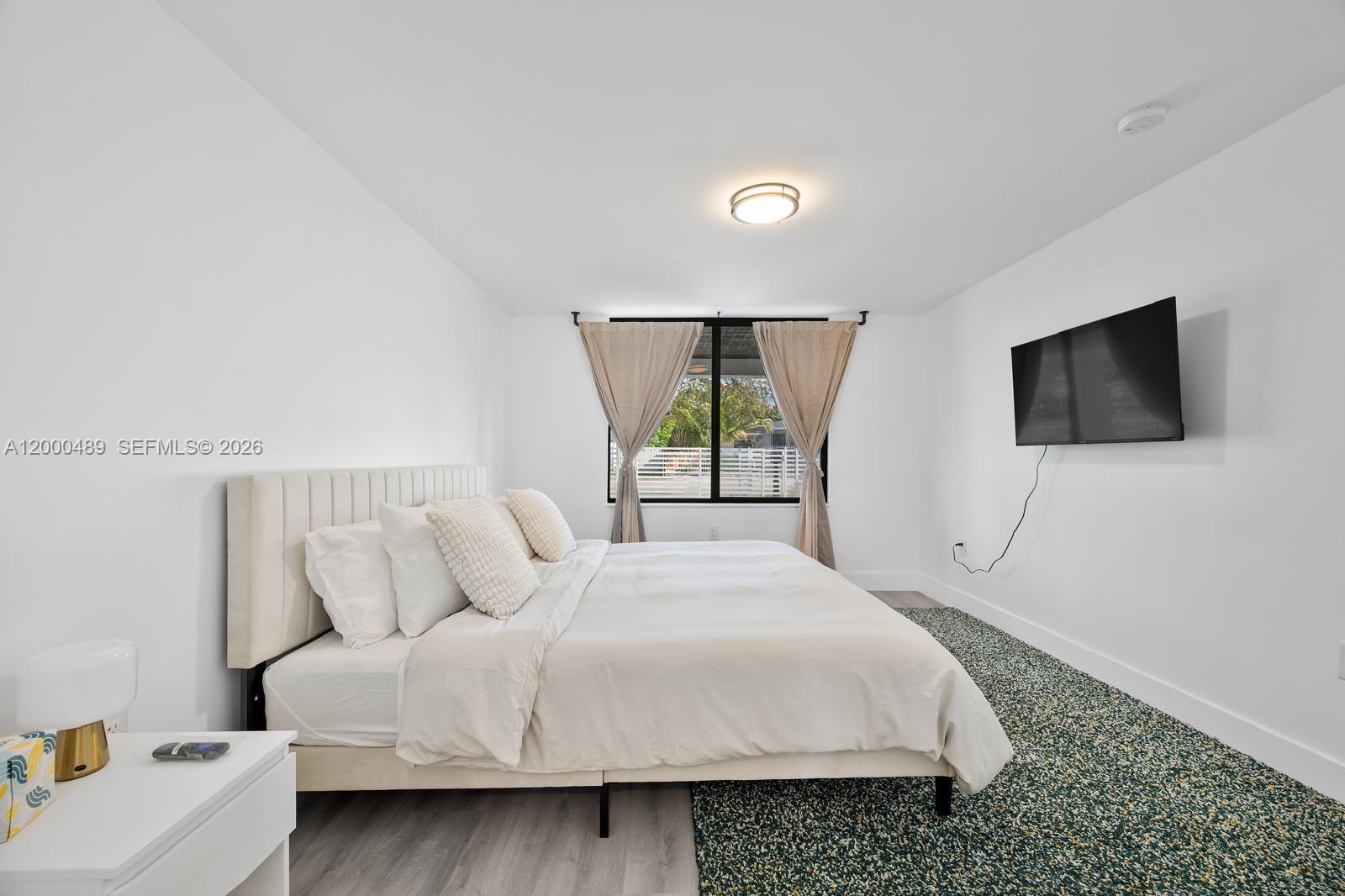11730 Northwest 3rd Avenue Miami, FL 33168 - Photo 10 of 39 a bedroom with a bed and a flat screen tv