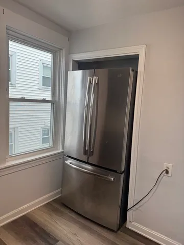 a view of empty room with wooden floor and window