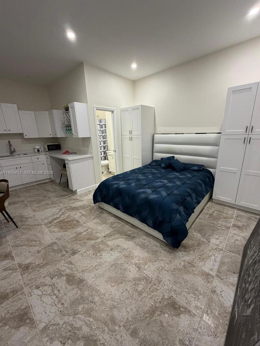 27264 Southwest 132nd Place, Unit A Homestead, FL 33032 - Photo 8 of 10 a spacious bedroom with a bed a table and cabinet
