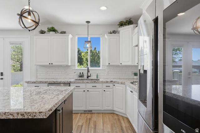 10676 Urban Rdg Cove South Jordan, UT 84095 - Photo 8 of 48 Kitchen featuring white shaker cabinetry, speckled countertops, a subway tile backsplash, stainless steel appliances, and wood-finish flooring