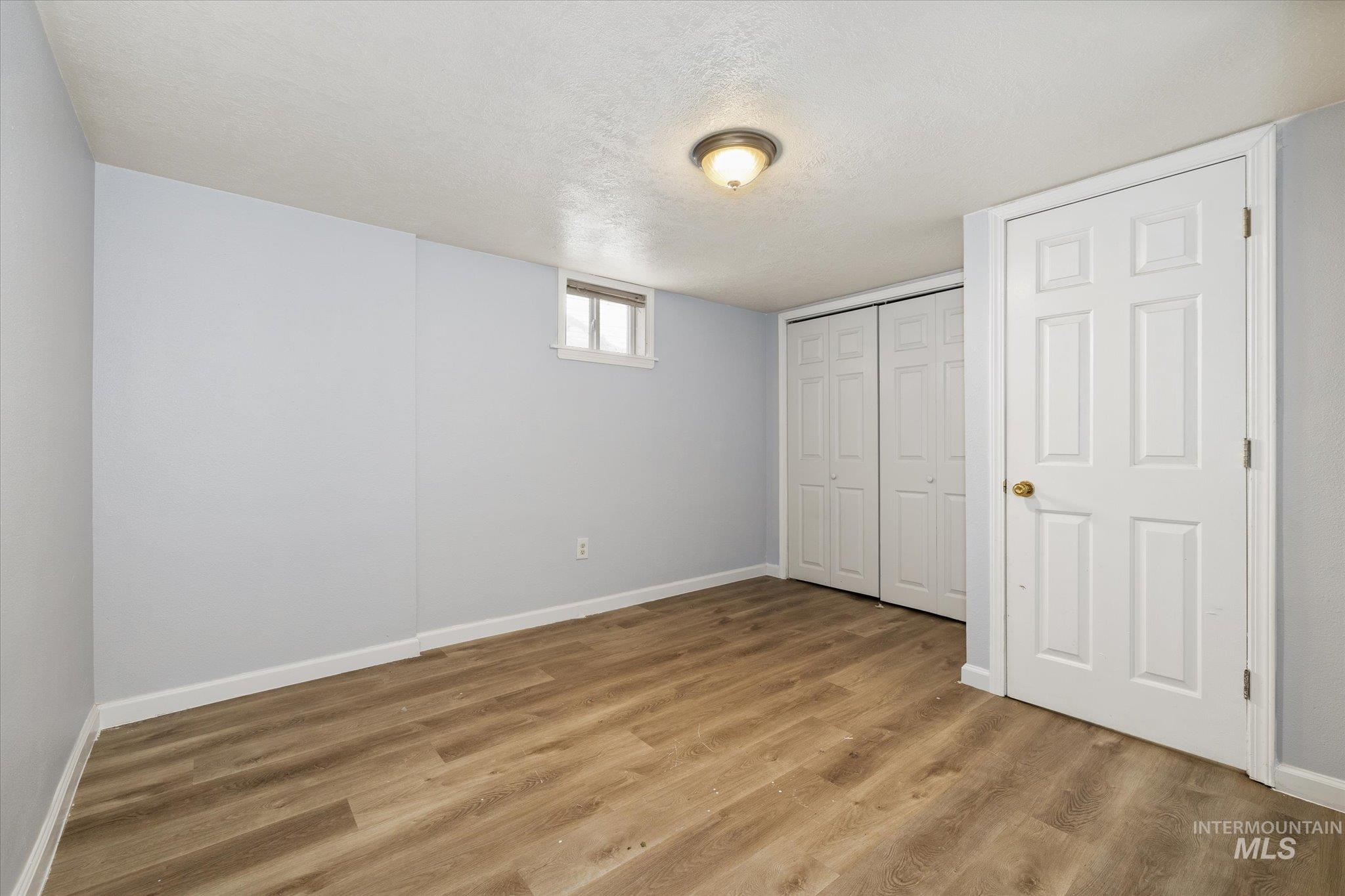 918 West 3rd Street Weiser, ID 83672 - Photo 27 of 36 Room featuring wood-finish flooring, two bi-fold closet doors, a single window, and a flush mount ceiling light fixture