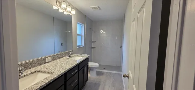 a bathroom with a granite countertop sink a mirror and a shower