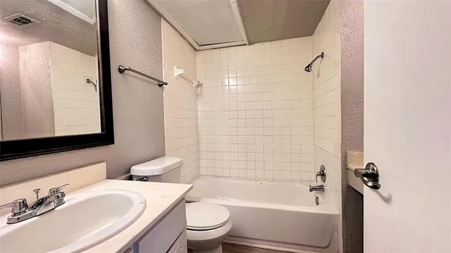 a bathroom with a bathtub shower sink mirror vanity and toilet