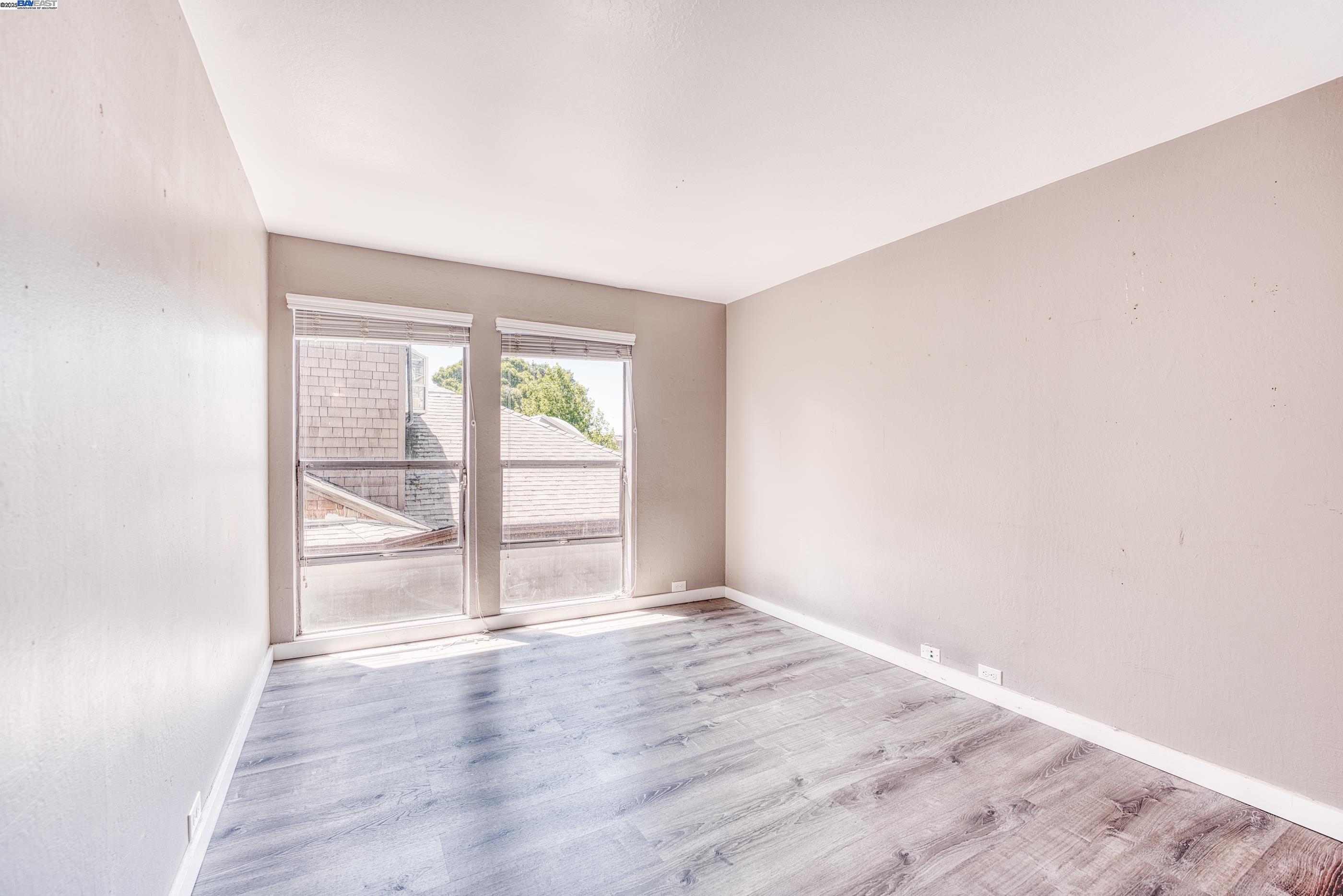 3815 Harrison Street, Unit 103 Oakland, CA 94611 - Photo 12 of 28 an empty room with wooden floor and windows