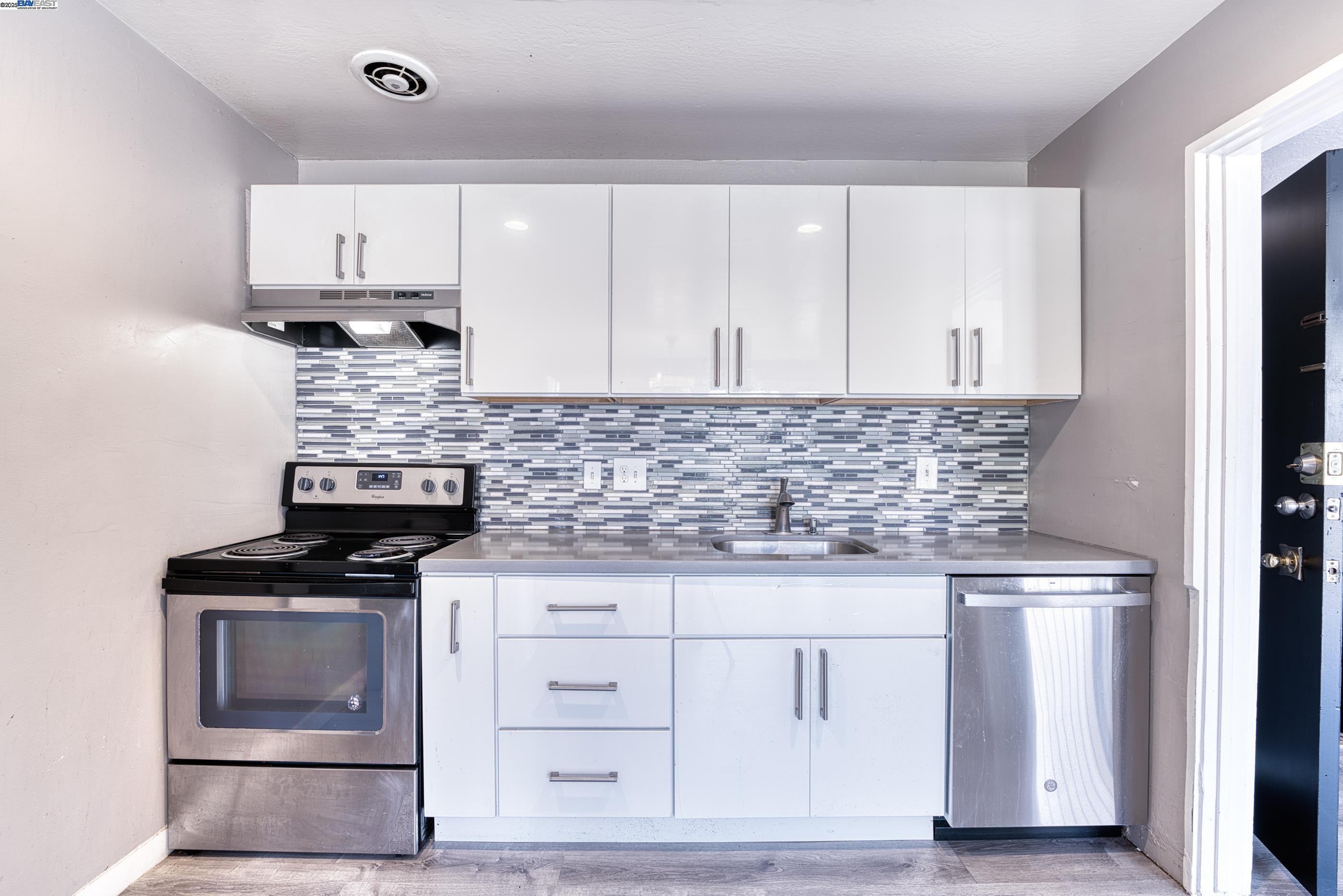 3815 Harrison Street, Unit 103 Oakland, CA 94611 - Photo 18 of 28 a kitchen with granite countertop white cabinets and stainless steel appliances