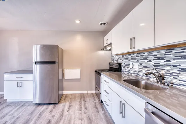 a kitchen with a sink a refrigerator and cabinets
