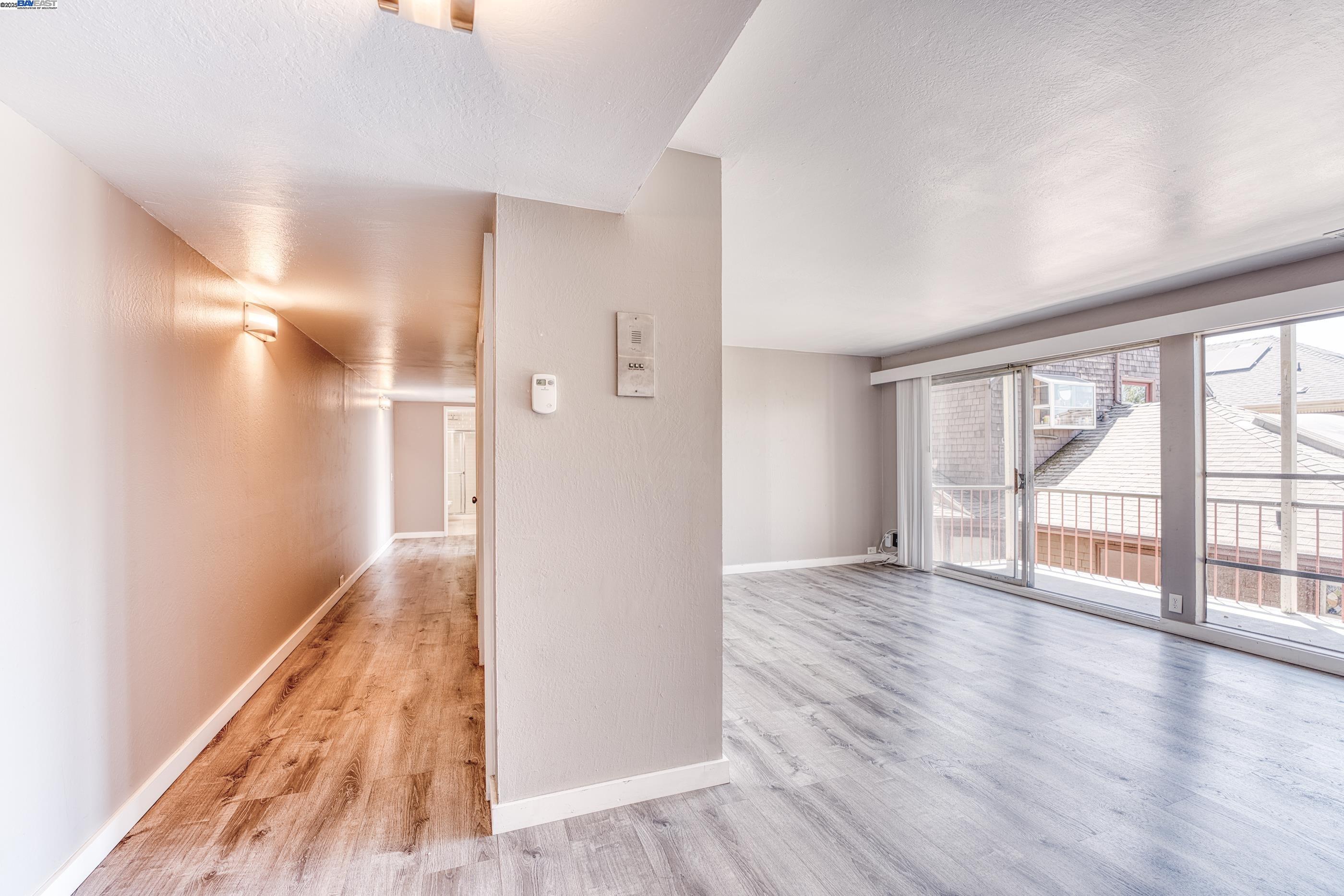 3815 Harrison Street, Unit 103 Oakland, CA 94611 - Photo 5 of 28 a view of an empty room with wooden floor and a window
